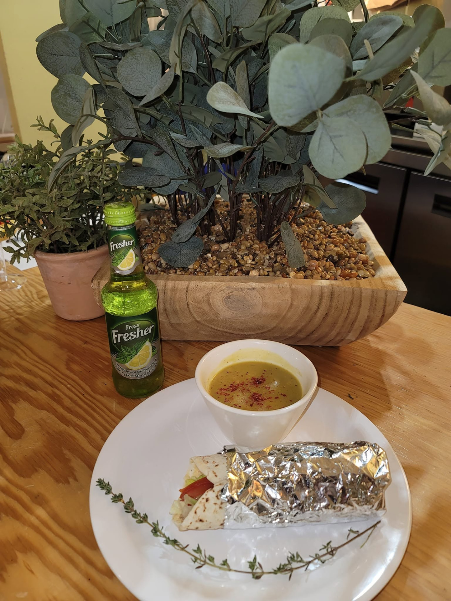 Bowl of lentil soup with sumac served with a wrapped sandwich