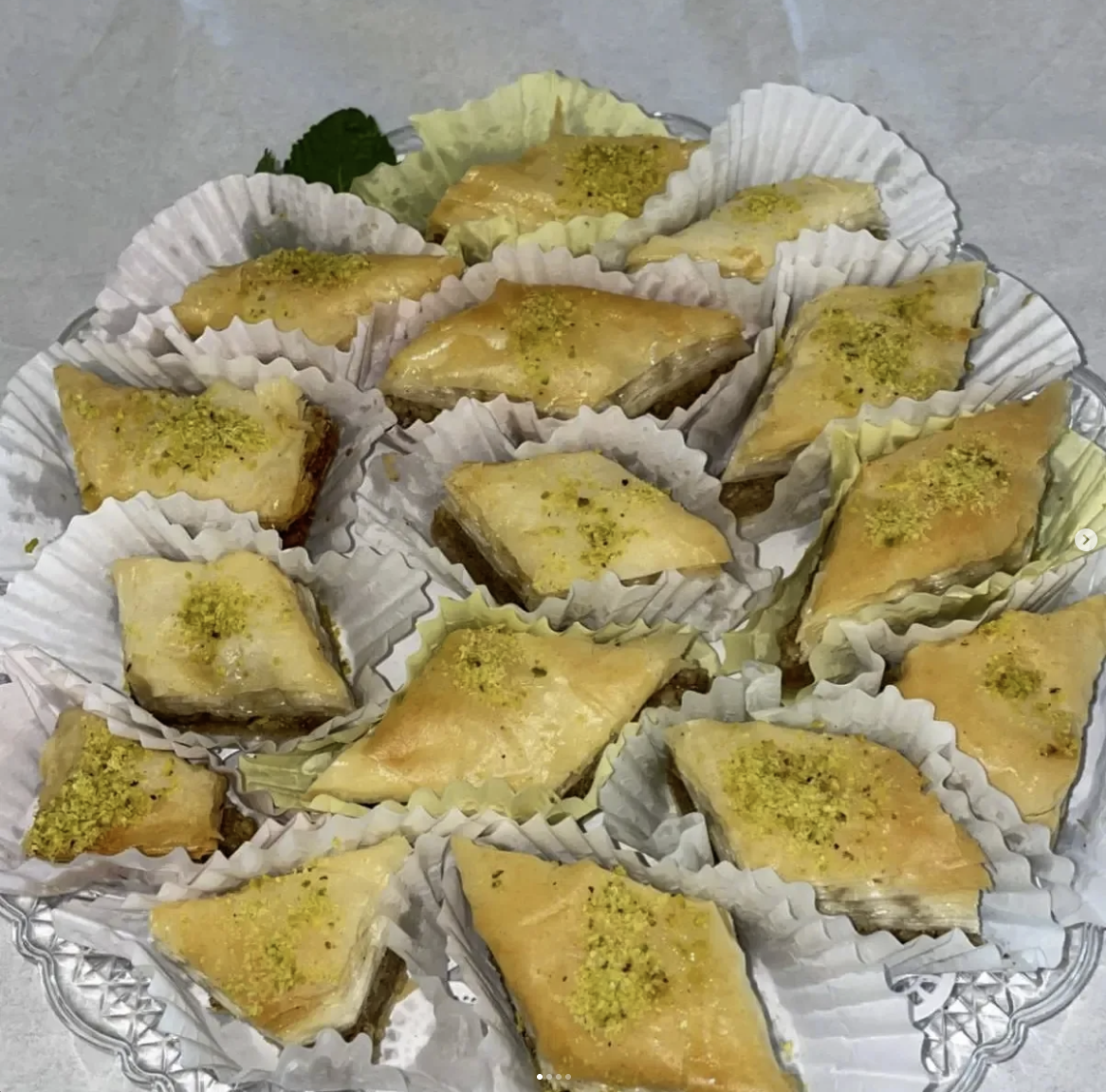 Crystal platter of pistachio topped baklava with fresh mint